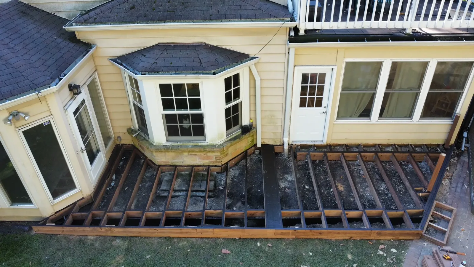 Exposed wood deck framing fitted around the bay window before the deck boards were installed